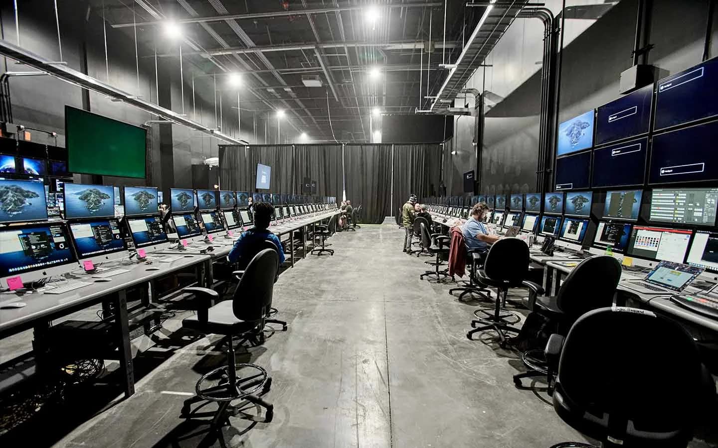 The Media Village at Worre Studios — two long rows of iMac workstations running event-management software, operators seated along each side.