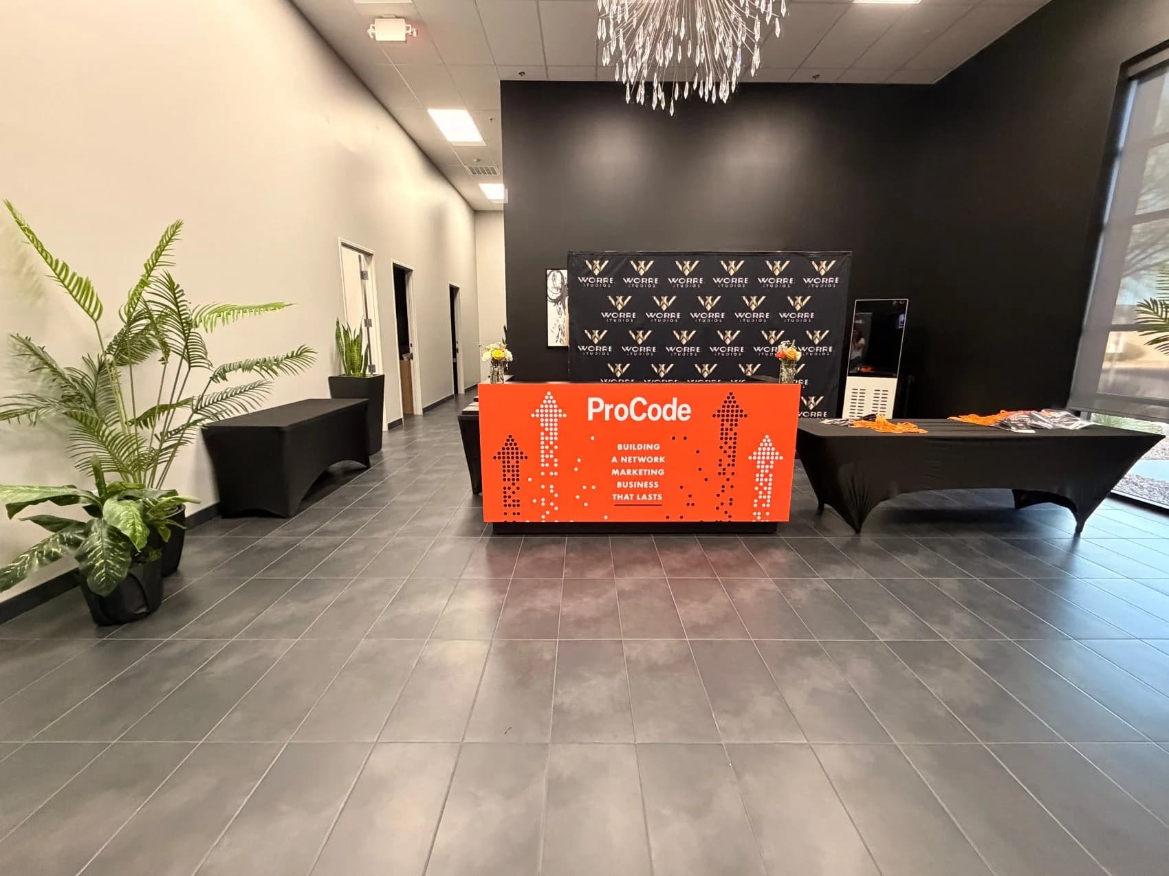 The studio lobby set for check-in — a branded ProCode registration desk and Worre Studios step-and-repeat with orange florals.