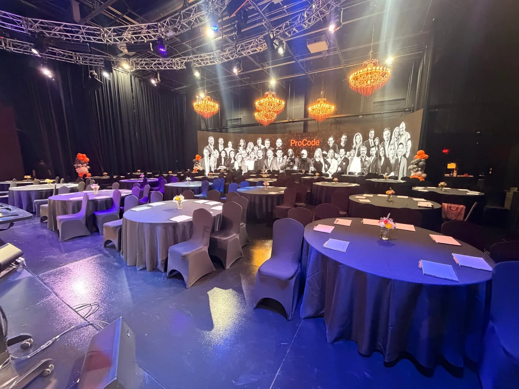 The studio set as a banquet for ProCode — rounds of draped tables and chandeliers facing a large ProCode team backdrop.