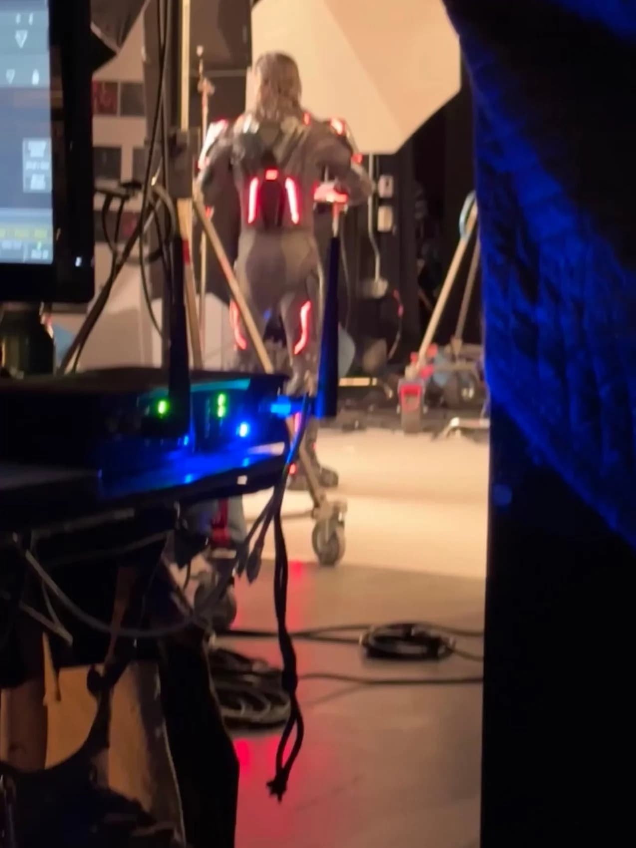 A lighting console glowing in the foreground as a costumed performer stands lit on the set behind it.
