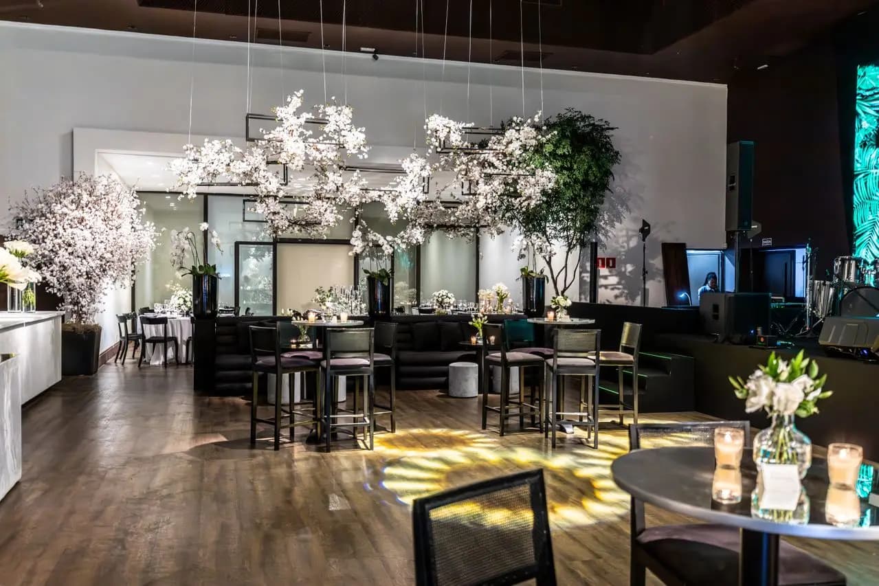 A dressed event venue with tables, floral arrangements, and a stage.